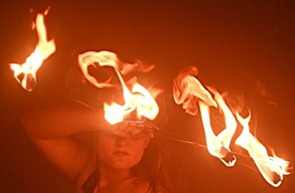 Hellgelbe Flammen vom Feuerfächer erscheinen wie eine Maske vor dem Gesicht der Frau Glutrabe.